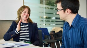 Manager and team member having a strengths-based conversation in a professional setting.